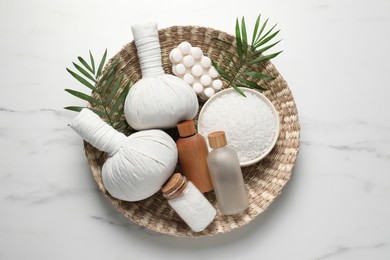 Photo of Composition with herbal massage bags and other spa products on white marble table, top view