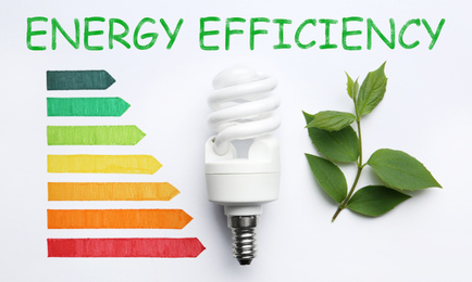 Flat lay composition with energy efficiency rating chart, fluorescent light bulb and leaves on white background