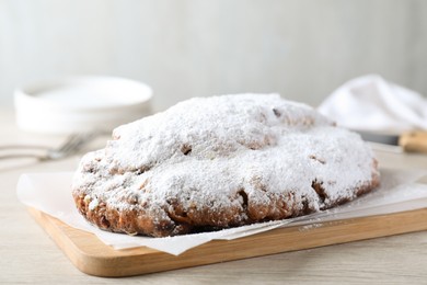 Delicious Stollen sprinkled with powdered sugar on wooden table
