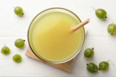 Photo of Tasty gooseberry juice on white wooden table, flat lay