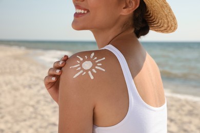 Young woman with sun protection cream on shoulder at beach, closeup