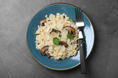 Photo of Delicious risotto with cheese and mushrooms on dark grey table, top view