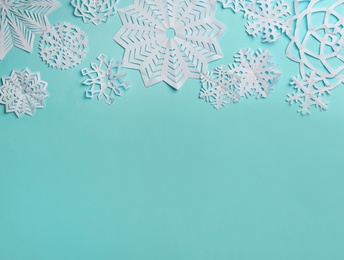 Flat lay composition with paper snowflakes on cyan background. Space for text
