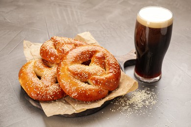 Tasty pretzels and glass of beer on grey table
