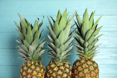 Photo of Fresh ripe juicy pineapples on light blue wooden background