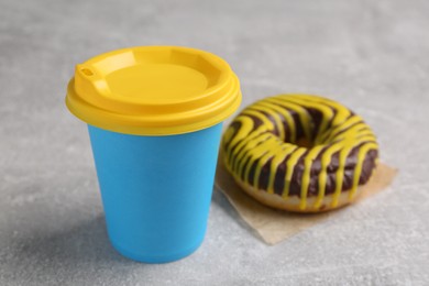 Photo of Tasty frosted donut and hot drink on light grey table