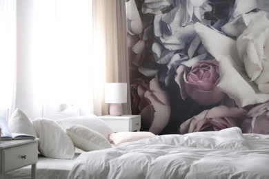 Comfortable bed near wall with floral wallpaper. Stylish room interior
