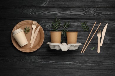 Flat lay composition with disposable tableware and green twigs on black wooden background