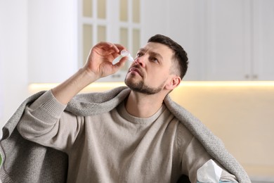Ill man using nasal drops at home