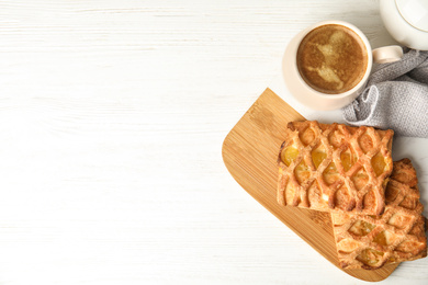 Fresh tasty pastries and coffee on white wooden table, flat lay. Space for text