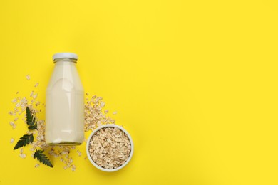 Vegan milk and oat flakes on yellow background, flat lay. Space for text