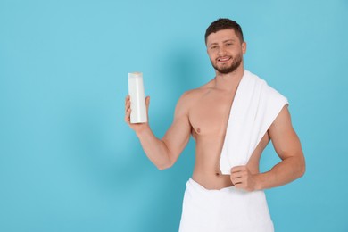 Shirtless young man holding bottle of shampoo on light blue background, space for text