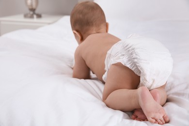 Cute baby in dry soft diaper on white bed, back view. Space for text