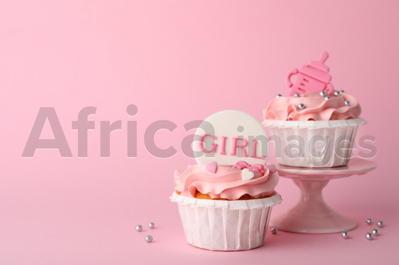 Photo of Baby shower cupcakes with toppers on pink background, space for text