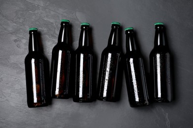 Photo of Tasty beer in bottles on black background, flat lay