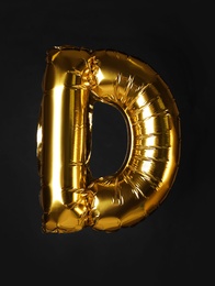 Photo of Golden letter D balloon on black background