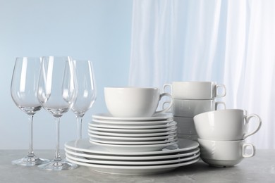 Photo of Set of clean dishware and glasses on grey marble table