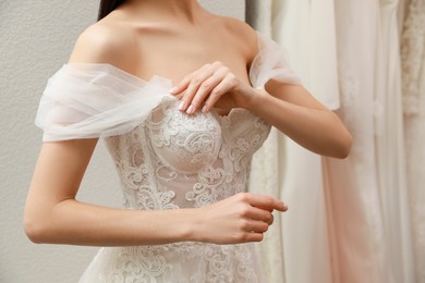 Woman trying on beautiful wedding dress indoors, closeup