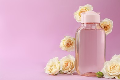 Bottle of micellar water and beautiful roses on light pink background. Space for text