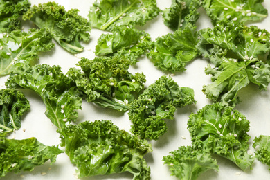 Raw cabbage leaves on parchment paper, closeup. Preparing kale chips