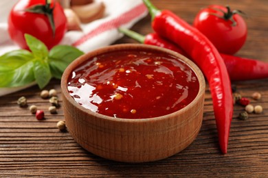 Spicy chili sauce in bowl on wooden table