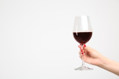 Woman holding glass of red wine on white background