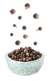 Many different peppercorns falling into bowl on white background