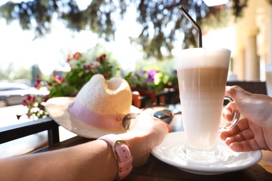 Young woman with coffee at table in outdoor cafe, closeup