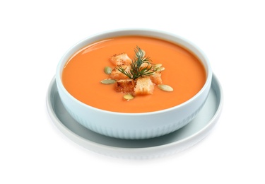 Tasty creamy pumpkin soup with croutons, seeds and dill in bowl on white background