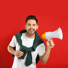 Young man with megaphone on red background