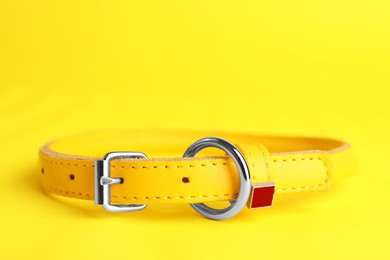 Leather dog collar on yellow background, closeup. Space for text