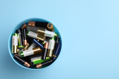 Image of Used batteries in bucket on light blue background, top view. Space for text