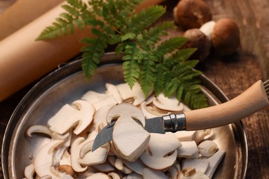 Cut mushrooms and knife on wooden table, closeup