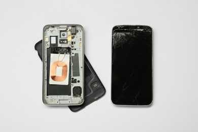 Damaged smartphone on white background, flat lay. Device repairing
