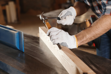 Professional carpenter working with wooden plank in workshop, closeup