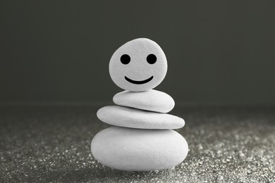 Stack of stones with drawn happy face on grey background. Zen concept