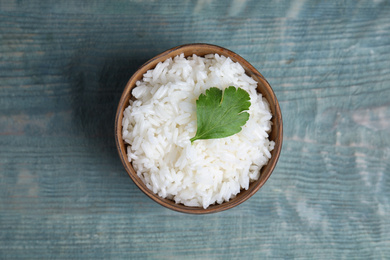 Bowl with tasty cooked rice on light blue wooden table, top view