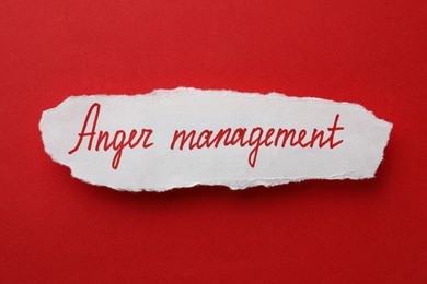 Sheet of white paper with words Anger Management on red background, top view
