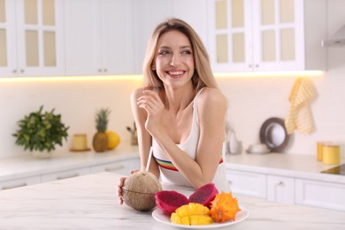 Photo of Young woman with exotic fruits in kitchen