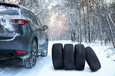 Snow tires near car on road in winter