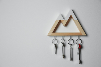Wooden key holder on light grey wall. Space for text