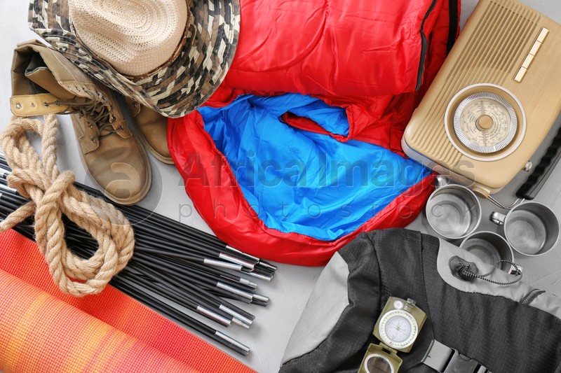 Flat lay composition with sleeping bag and camping equipment on grey background