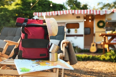 Photo of Red backpack and travel accessories on deck chair outdoors. Summer trip