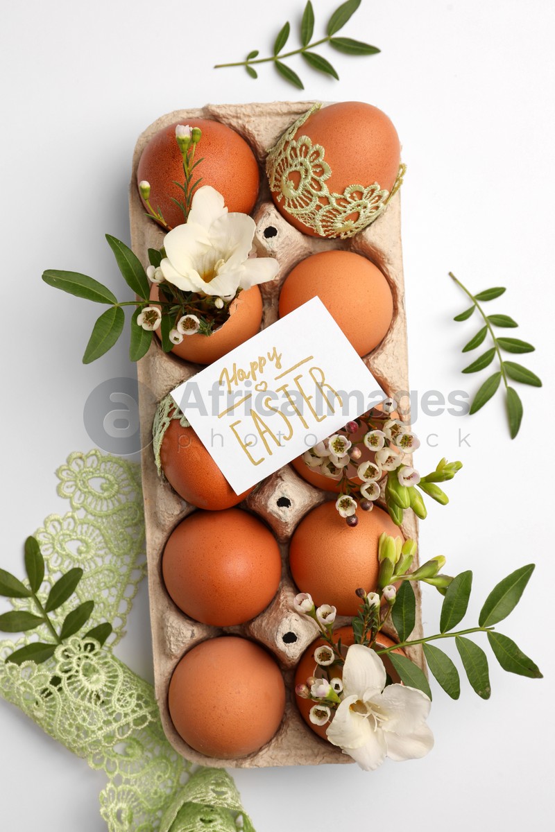 Photo of Card with words Happy Easter, eggs and green twigs on white background, flat lay