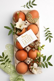 Photo of Card with words Happy Easter, eggs and green twigs on white background, flat lay