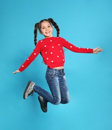 Portrait of little girl jumping on color background