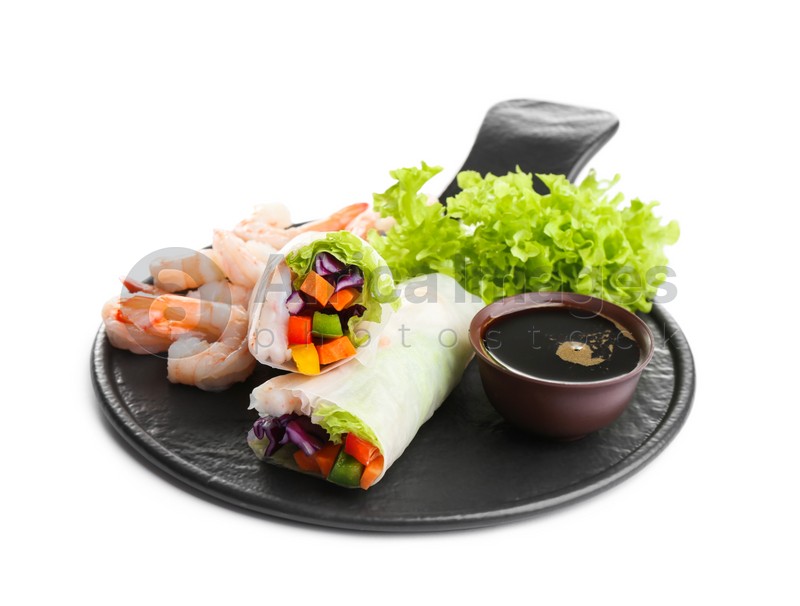 Delicious rolls wrapped in rice paper and soy sauce on white background