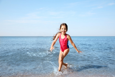 Cute little child having fun in sea on sunny day. Beach holiday