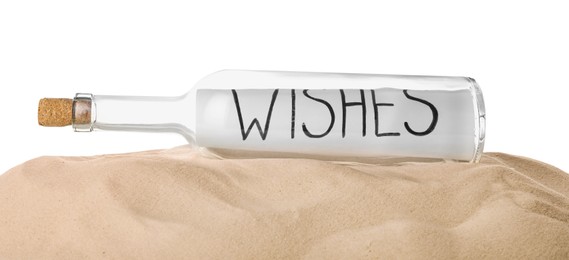 Corked glass bottle with Wishes note on sand against white background