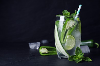 Photo of Spicy cocktail with jalapeno, cucumber, lime and mint on black table. Space for text